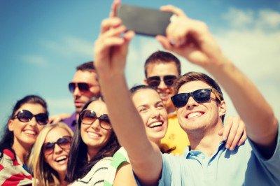 summer, holidays, vacation and happiness concept - group of friends taking picture with smartphone