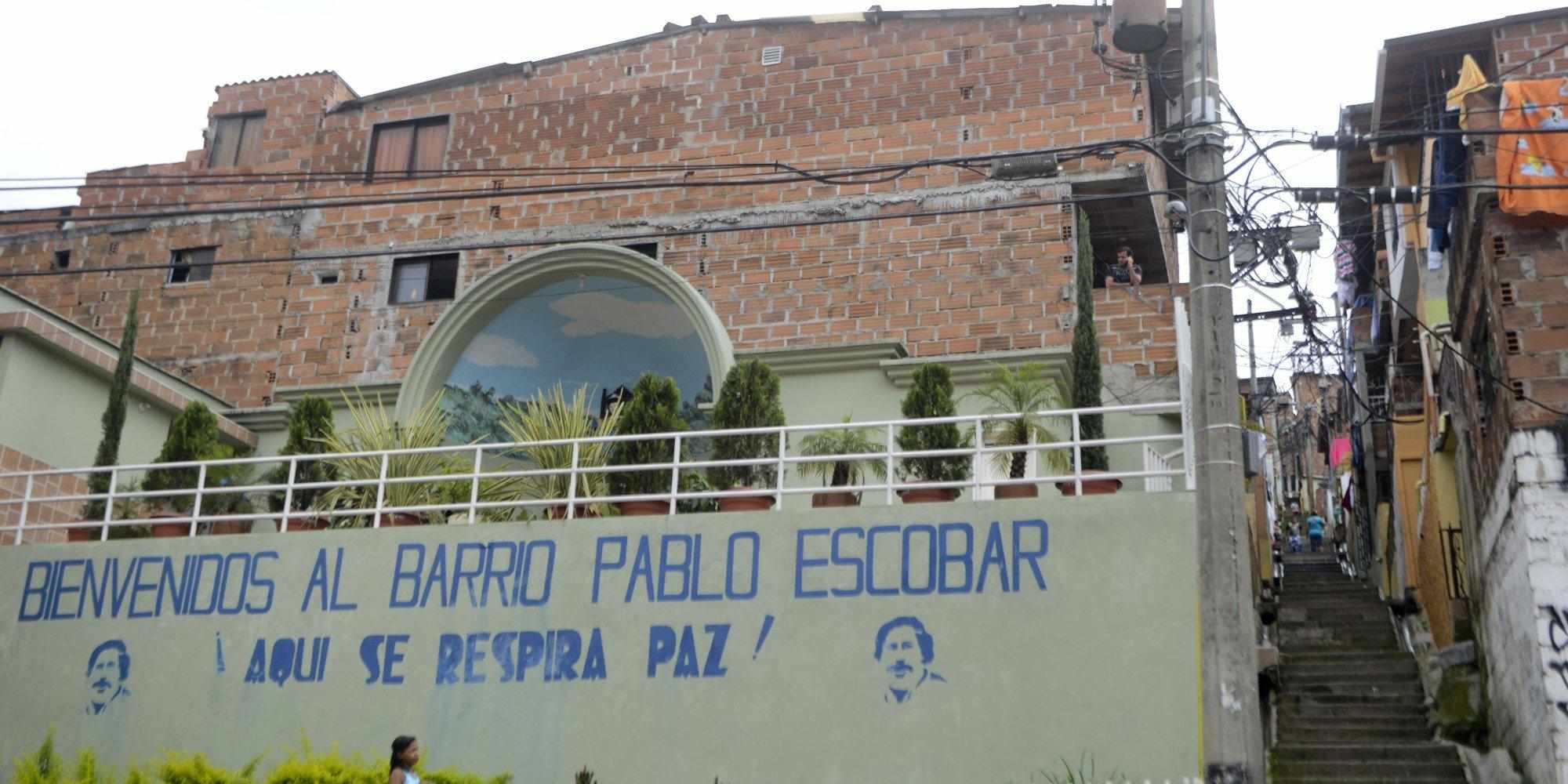 TO GO WITH AFP STORY BY ARIELA NAVARRO A girl walks past a wall with an inscription reading "Welcome to the Pablo Escobar neighborhood. Here we breathe peace!" at Pablo Escobar neighborhood, on November 24, 2013 in Medellin, Antioquia department, Colombia. December 2, 2013 marks the 20th anniversary Escobar's death. AFP PHOTO/Raul ARBOLEDA (Photo credit should read RAUL ARBOLEDA/AFP/Getty Images)