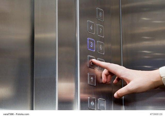Female finger presses the button on the glowing panel elevator