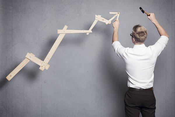 Concept: Building your own career or business. Young businessman installing upward arrow on floating business graph with positive trend, isolated on grey background.