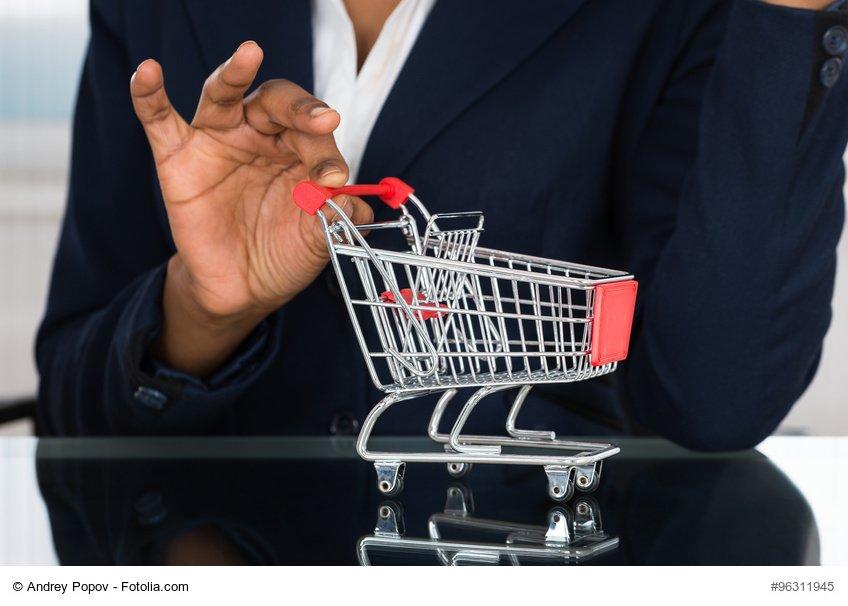 Close-up Of Businesswoman Holding Cart On Desk