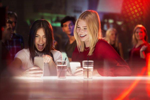 Two young beautiful girls looking at smartphone and laughing