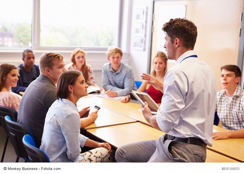 Teacher With College Students Giving Lesson In Classroom