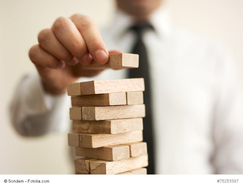 Businessman putting last block to the tower