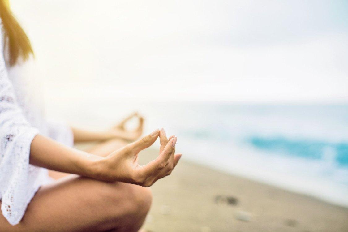 Young girl is meditating on the beach