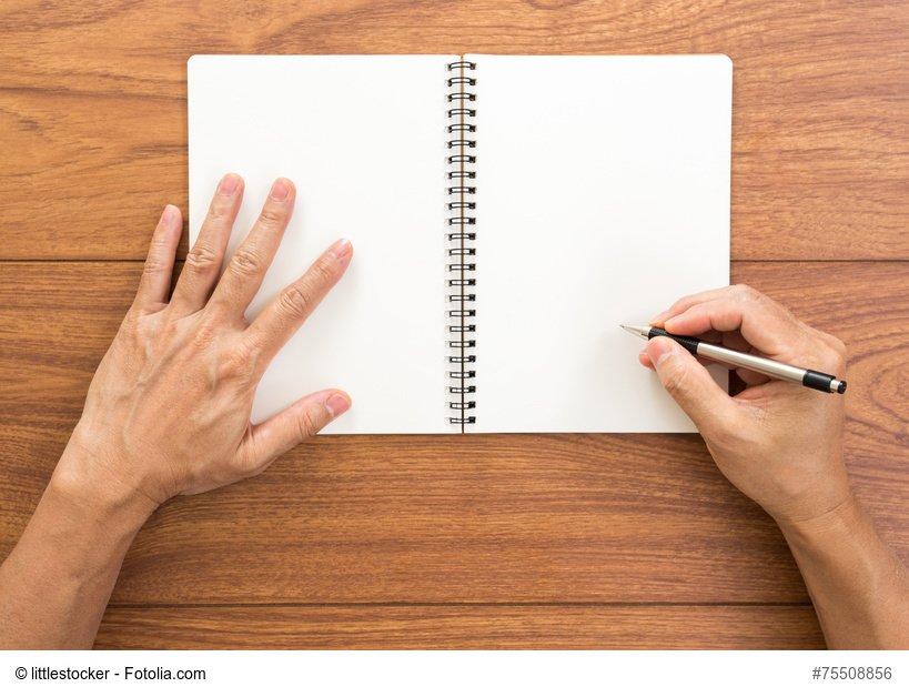 Man hand writing notebook on wood background