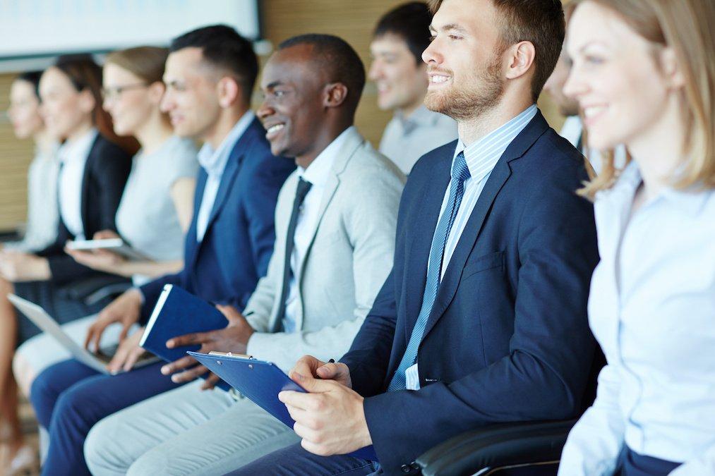 Happy young man making notes during presentation