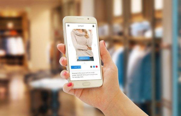 Woman on line shopping with smart phone. Clothing store in the background.