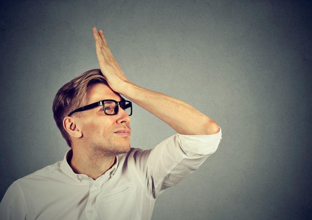 Regrets wrong doing. Silly young man, slapping hand on head having a duh moment isolated on gray background. Negative human emotion facial expression feeling, body language, reaction
