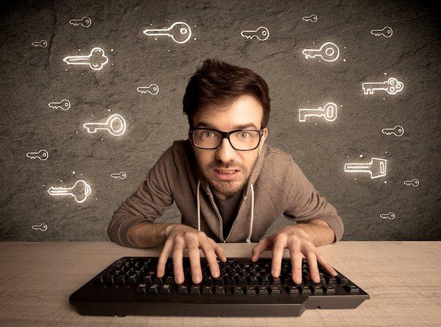 A young internet geek working online, hacking login passwords of social media users concept with glowing drawn keys on the wall