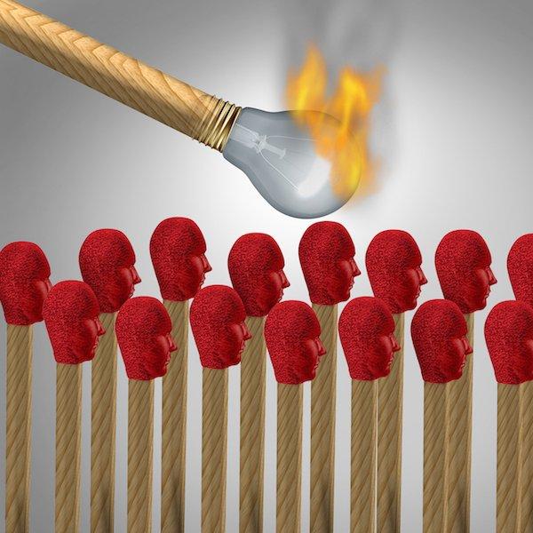 Ideas that catch on concept as a viral marketing symbol and spreading a popular idea or propaganda and social brainwashing communication icon as a lit matchshaped as a light bulb lighting a group of other matches shaped as human heads.